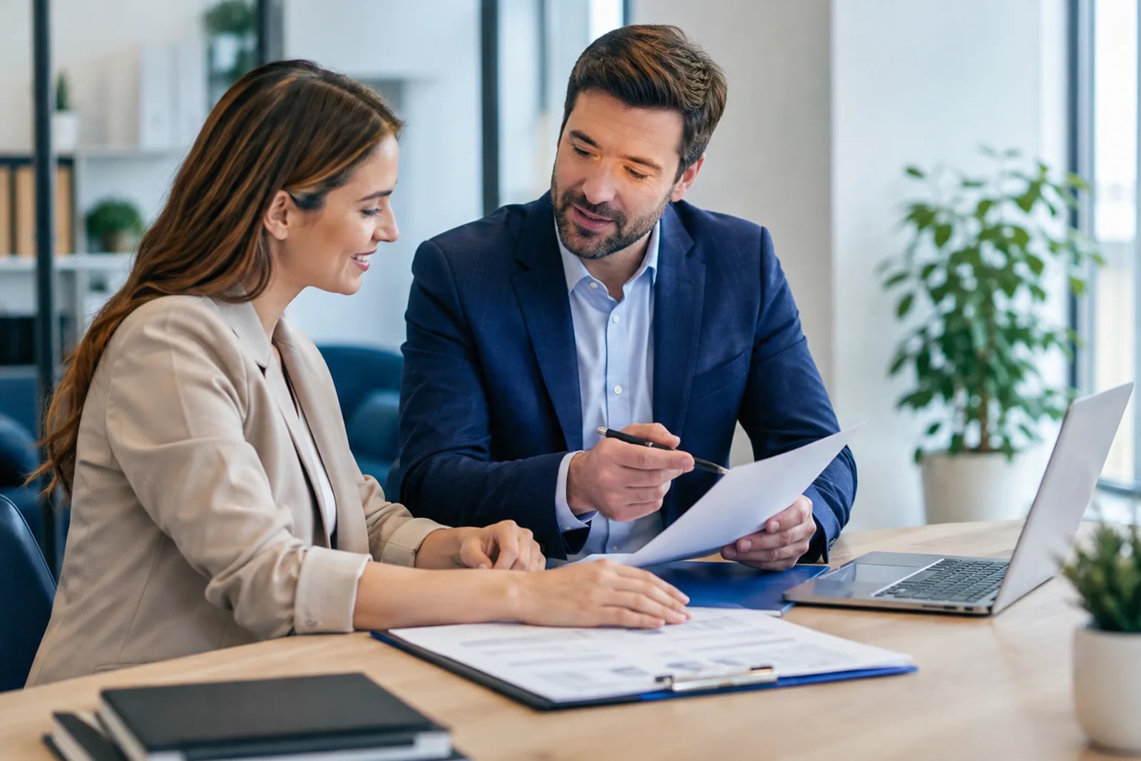 Consultora mostrando documento a um cliente durante atendimento, com notebook aberto na mesa